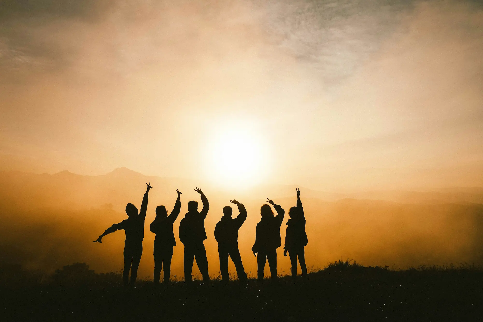 groupe de personne devant un couché de soleil